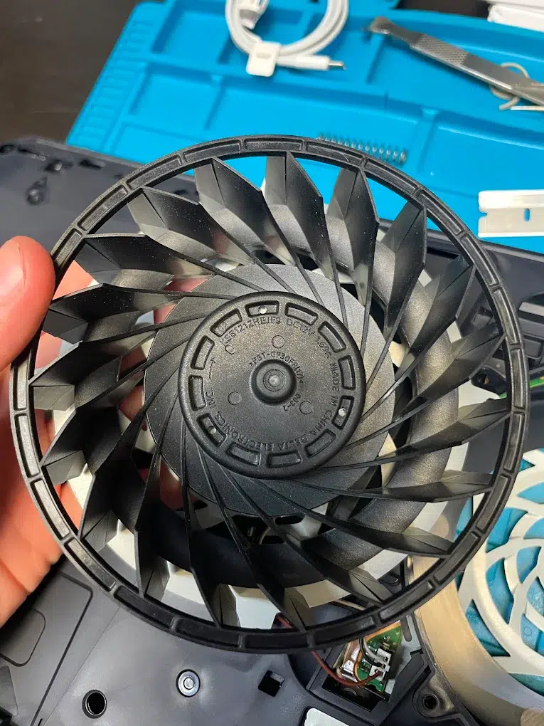 Close-up of a PS5 cooling fan removed for cleaning on the Wesley Chapel repair bench