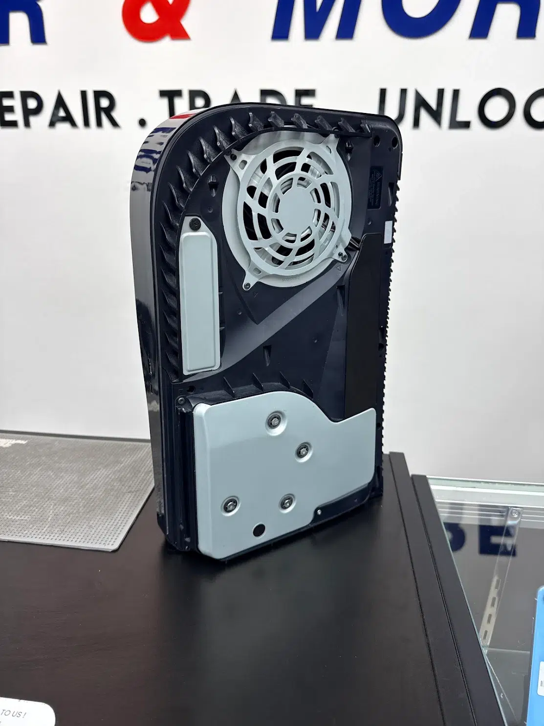 PS5 with its side panel removed showing the cooling fan and shield during a repair at Phone Repair & More Wesley Chapel